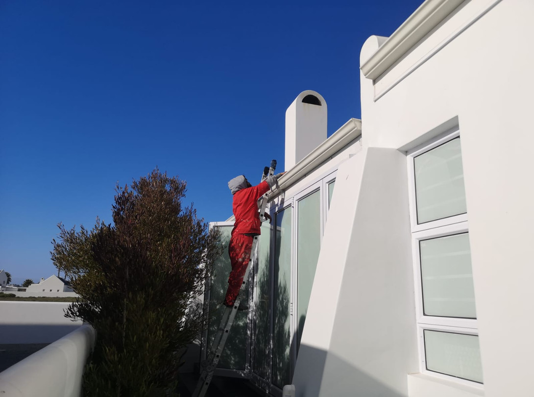Technician on a ladder working at the roofline gutter