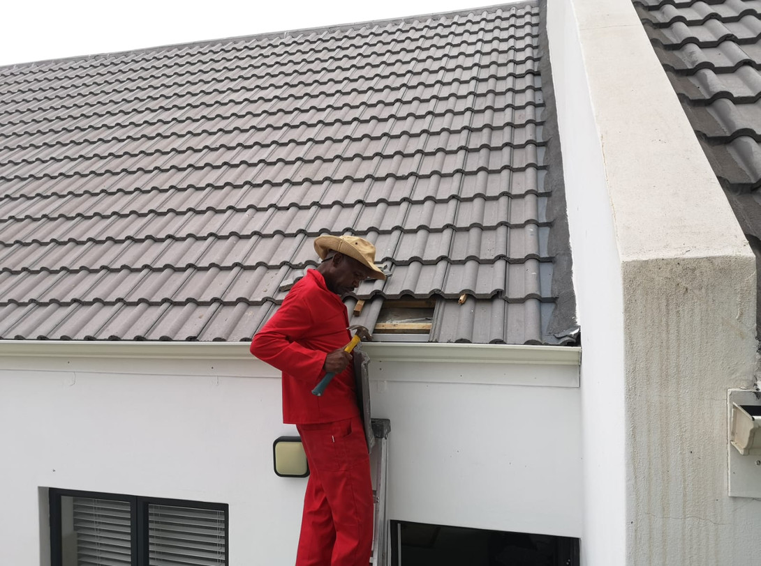 Technician repairing a tile on a pitched roof